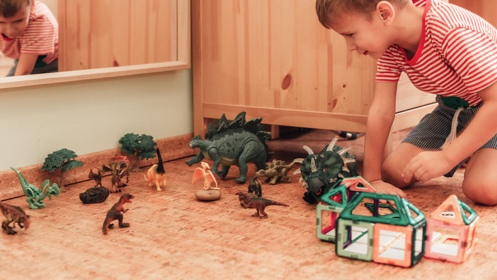 Happy boy plays with toy on the cork flooring