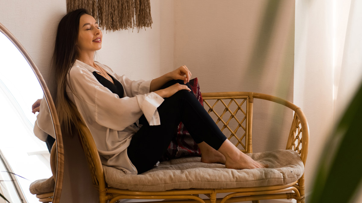 Young beautiful woman sitting on bench at home feeling relaxed