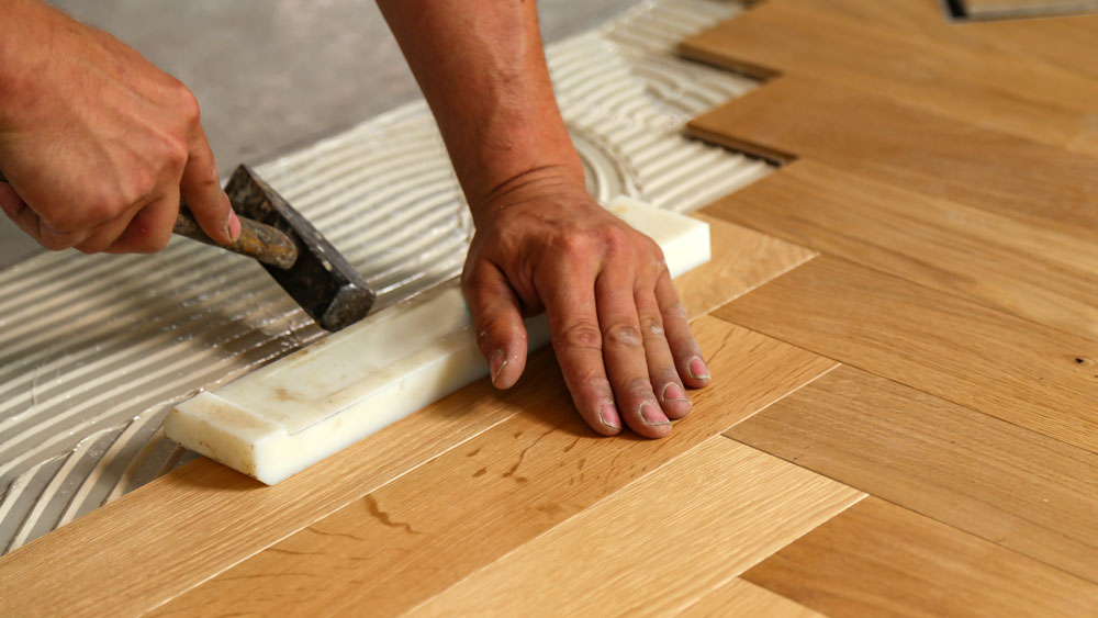 Worker installing parquet patterned timber flooring