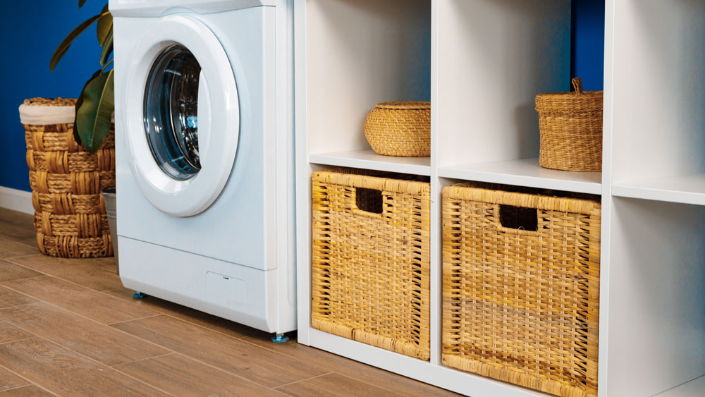 Washing machine in laundry room with laminate flooring