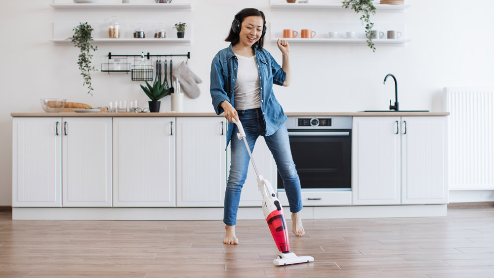 Woman vacuuming floor while listening music