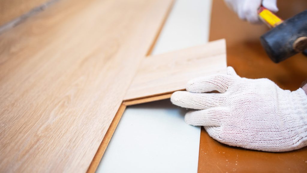 Master with a rubber mallet knocks on the laminate