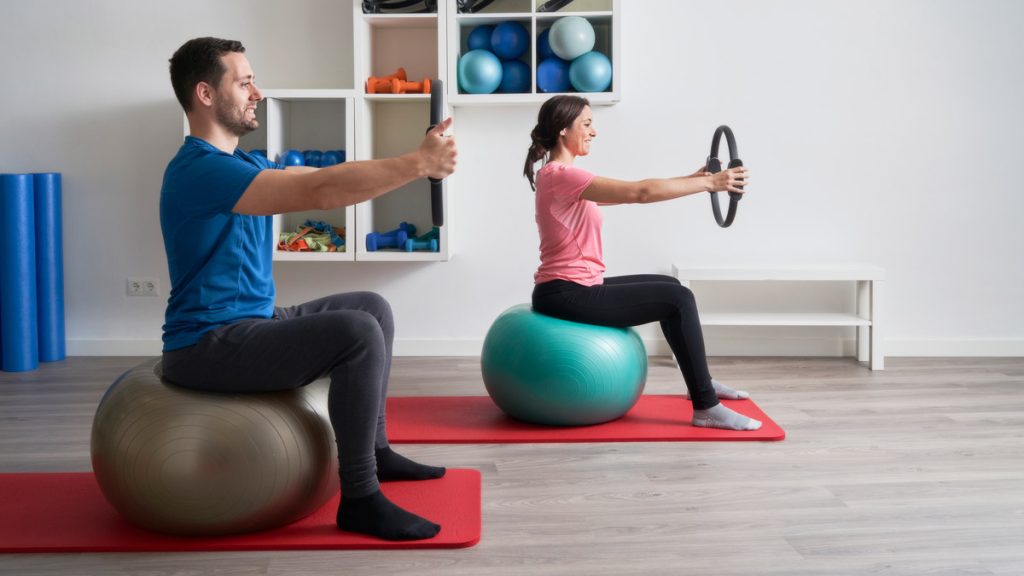 Young man and woman doing gymnastics in home gym