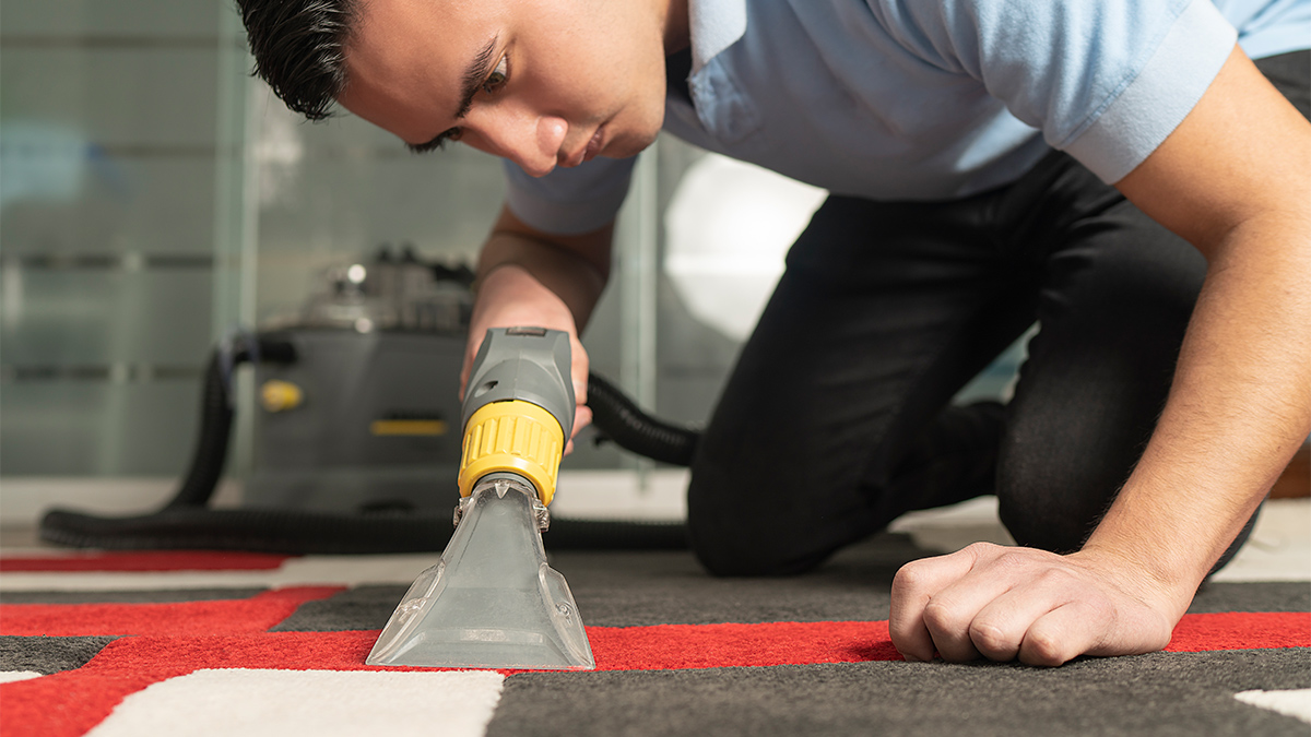 Man removing carpet stains using a carpet cleaning tool