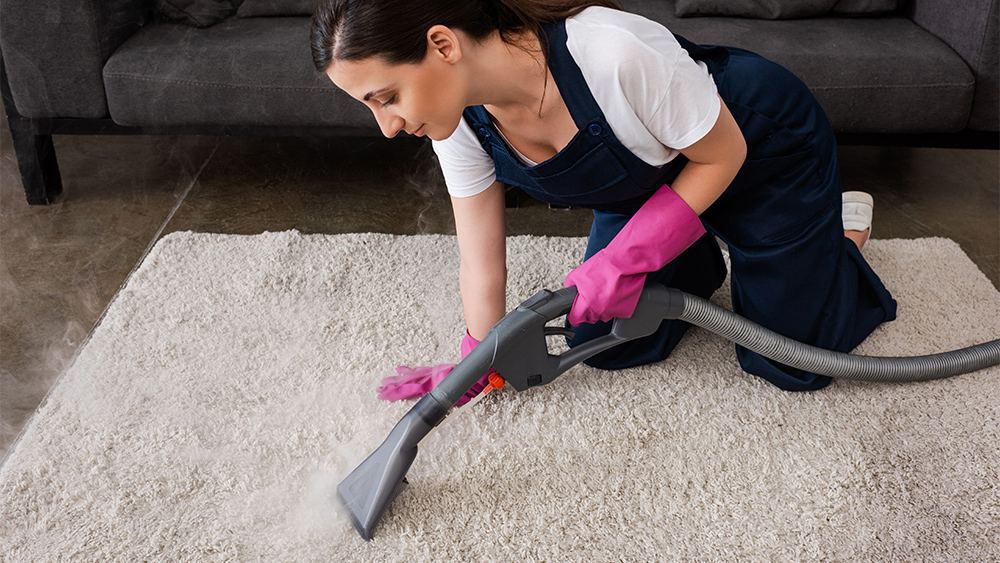 Woman using steam vacuum for cleaning carpet