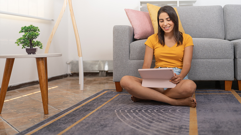 Young woman using tablet to watch videos on smart carpet