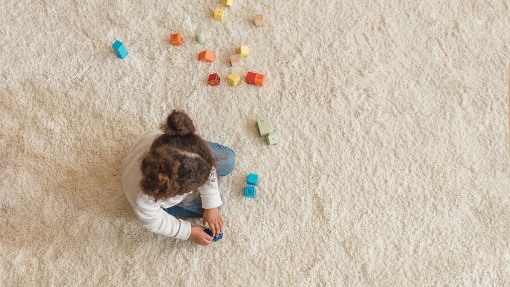 Little girl playing with cubes on a low-VOC carpet