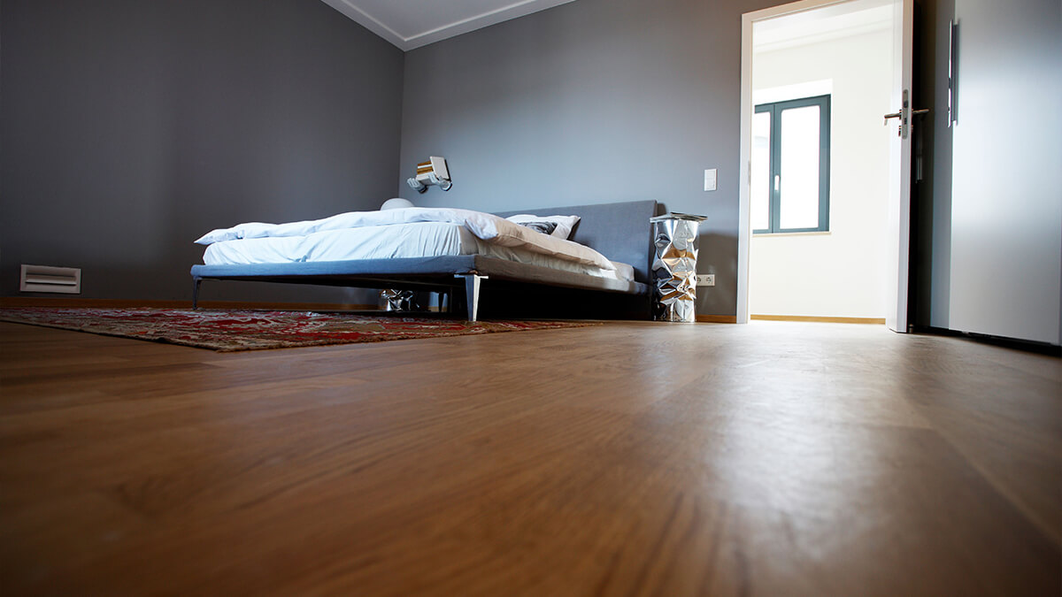 Interior of a bedroom with minimalist furniture and laminate flooring