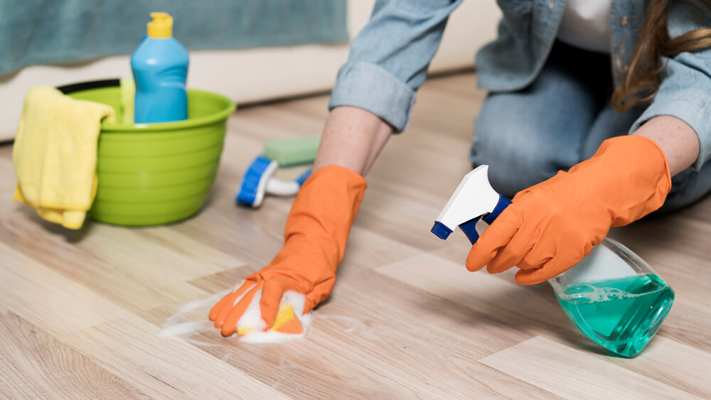 Woman cleaning laminate flooring with chemical materials