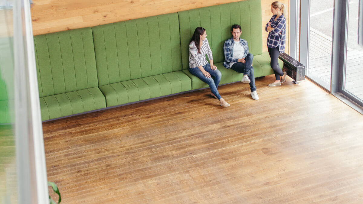 Big salon with timber flooring and three people standing there