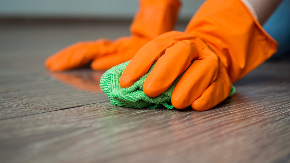 Hands with rubber gloves cleaning floor