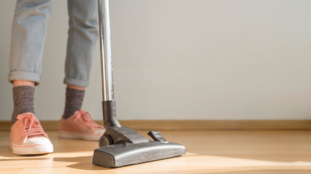 Woman using vacuum cleaner on bamboo flooring